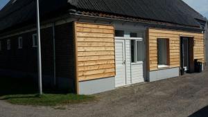 ein kleines Haus mit seitlicher Holzvertäfelung in der Unterkunft Apartment Vredehof in Sint Maartensbrug