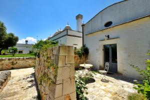 un patio con tavolo e sedie di fronte a un edificio di Masseria Trulli e Vigne a Martina Franca