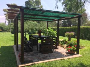 a wooden pergola with a table in a garden at Casale Del Borgo in Hermada