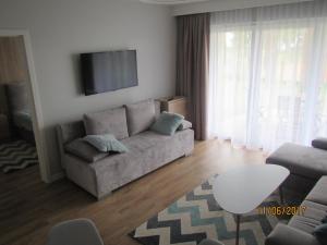 a living room with a couch and a flat screen tv at Apartament z ogrodkiem in Pogorzelica
