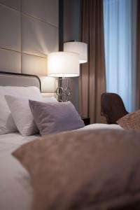 a bedroom with two beds with a lamp and a chair at Hotel Riva by Aycon in Petrovac na Moru