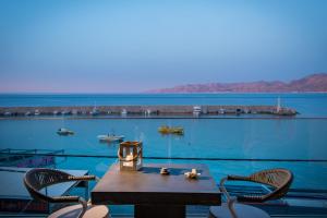 Una mesa y sillas con vista al agua. en Cosmopolis Crete Suites, en Hersonissos