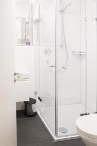 a white bathroom with a shower and a toilet at Taste Style Hotel Bären Auggen in Auggen