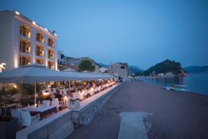 a row of tables and umbrellas next to a body of water at Hotel Riva by Aycon in Petrovac na Moru