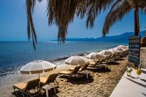 una fila de sillas y sombrillas en una playa en Cosmopolis Crete Suites en Hersonissos
