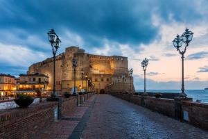 un gran castillo sentado al lado del océano al atardecer en Chiaia Suites, en Nápoles