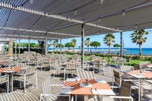 Un restaurante con mesas y sillas y el océano. en Estival ElDorado Resort, en Cambrils