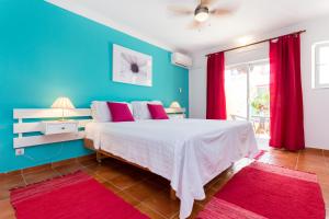 1 dormitorio azul con cama blanca y cortinas rojas en Vila Graciosa - Tranquility Oasis, en Lagos