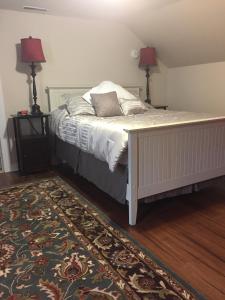 1 dormitorio con 1 cama con 2 lámparas y 1 alfombra en Stephen Clay Homestead Bed and Breakfast, en Candia