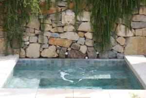 a swimming pool next to a stone wall at Chambres et tables d'hôtes , spa et séjour bien être , Le Clos de la Chèvre Sud in La Cadière-dʼAzur