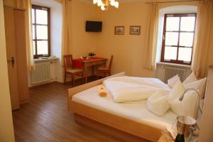 a bedroom with a bed and a table and windows at Gasthaus Kerber in Fürstenstein