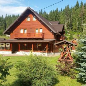 a large wooden house in the middle of a yard at Pensiunea Putnisoara in Putnişoara