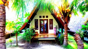 a house with a palm tree in front of it at Saeri Matahari Bungalow in Gili Islands