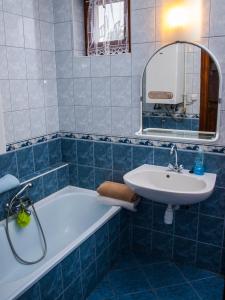 a blue tiled bathroom with a sink and a tub at Flora Apartman in Gyula