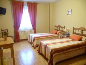 a hotel room with two beds and a window at Hostal Gogar in Puentenansa