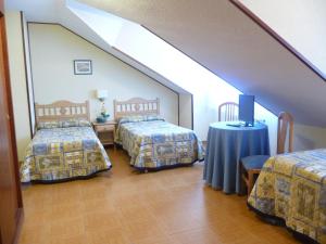 a attic room with two beds and a table at Hostal Gogar in Puentenansa