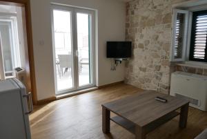 een woonkamer met een houten tafel en een televisie bij Guest house Jere Old Town in Rogoznica