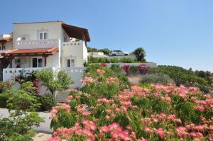 a garden with pink flowers in front of a house at Castri Village Hotel in Palekastron