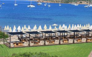um resort com cadeiras e guarda-sóis junto à água em Aegeon Beach Hotel em Sounio
