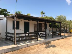 a pavilion with benches in front of a house at Camping Porto Miggiano in Santa Cesarea Terme
