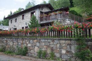 ein Steinhaus mit Blumen auf einem Zaun in der Unterkunft Agriturismo Al Castagneto in Mazzo di Valtellina