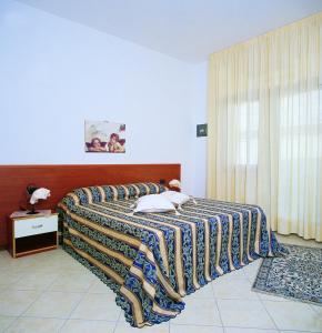 a bedroom with a bed with a striped blanket on it at Residence Vittoria in Alba Adriatica