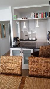 cocina con armarios blancos y sillas de mimbre en una habitación en Mehr Meer geht nicht en Sierksdorf