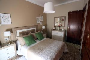 a bedroom with a bed with two green pillows at Apartamento Duque de Arcos in Arcos de la Frontera