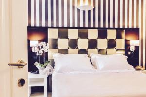 a bedroom with a white bed with a black and white headboard at JR Resort Logos Forte dei Marmi in Forte dei Marmi