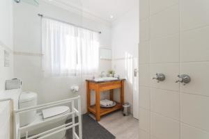 a white bathroom with a sink and a toilet at Rinkink Beach House in Wilderness