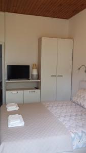 a white bedroom with a bed and a tv at Apartment Dinko in Cres