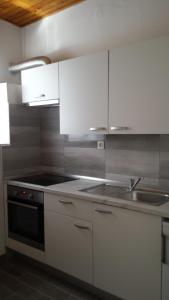 a kitchen with white cabinets and a stove top oven at Apartment Dinko in Cres