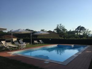 a swimming pool with chairs and umbrellas in a yard at Residence Casali Romei in Sarzana