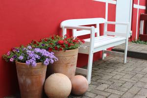 two buckets of flowers and a bench next to a building at Ferienwohnung zum Nordlicht in Bassum