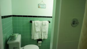 a green tiled bathroom with a toilet and towels at Atlantic Sands in Hampton