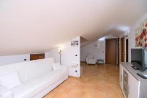 uma sala de estar com um sofá branco e uma televisão em Dominella 2 em Casal Velino