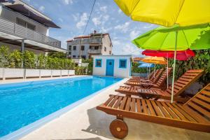 a group of chairs with umbrellas and a swimming pool at Apartments Gardelin Superior in Zadar