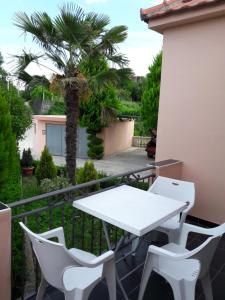 a white table and chairs on a balcony with a palm tree at Guest's house ''Lindi&Roni'' in Ulcinj