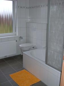 a white bathroom with a tub and a toilet at Nordsee - Residenz in Dornum