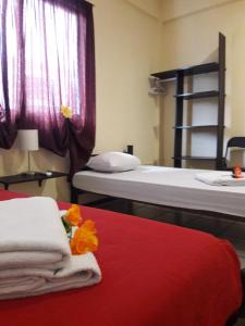 a room with two beds and a red bed with towels at Alme Hostel in Playa del Carmen