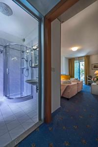 una habitación de hotel con ducha y un dormitorio en Hotel Meridianus, en Lignano Sabbiadoro