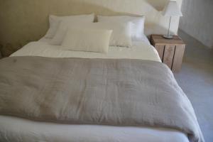a large bed with white sheets and pillows at Uzes, loft dans Moulin independant 18e siecle en bord de riviere piscine privee 15x3 in Uzès