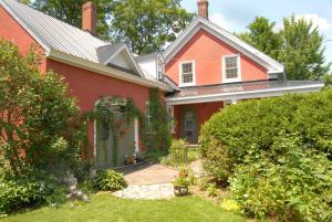 a red house with a garden in front of it at Le Passe-Partout in Cowansville