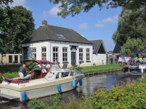 un barco estacionado frente a una casa en un río en B&B De Gouden Vlo en Donkerbroek