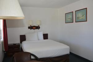 1 dormitorio con 1 cama blanca y 1 silla en Pacific Sunset Inn, en Brookings