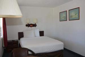 a bedroom with a white bed and a chair at Pacific Sunset Inn in Brookings