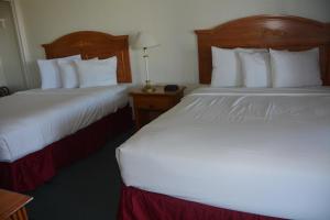 a hotel room with two beds with white sheets at Pacific Sunset Inn in Brookings +4 photos