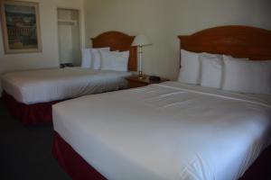 Habitación de hotel con 2 camas con sábanas blancas en Pacific Sunset Inn, en Brookings