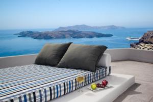 uma cama numa varanda com vista para o oceano em Amity Suites - Adults Only em Fira