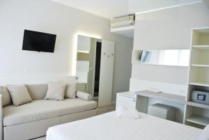 a white living room with a couch and a tv at Hotel Bologna in Lignano Sabbiadoro
